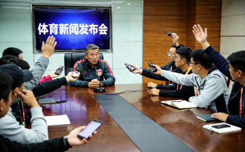 体育新闻发布厅内记者向教练提问的现场